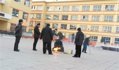1月3日下午5时许，五台县实验小学校园内，一名教职工将桶装机油淋在用木炭垒起的“旺火”堆上，为其助燃。